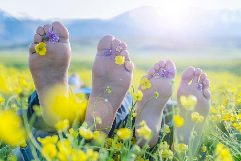 bare feet in grass with wildflowers, relaxed and carefree retreat moment