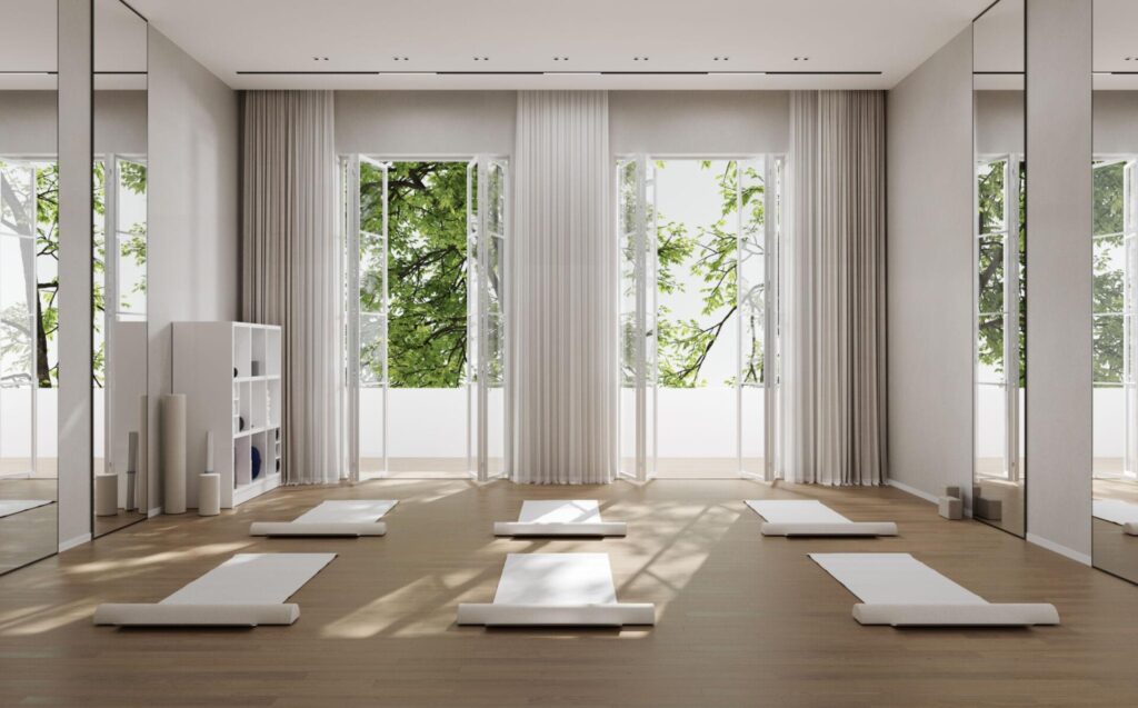 minimalist yoga retreat space with mats and natural light overlooking greenery