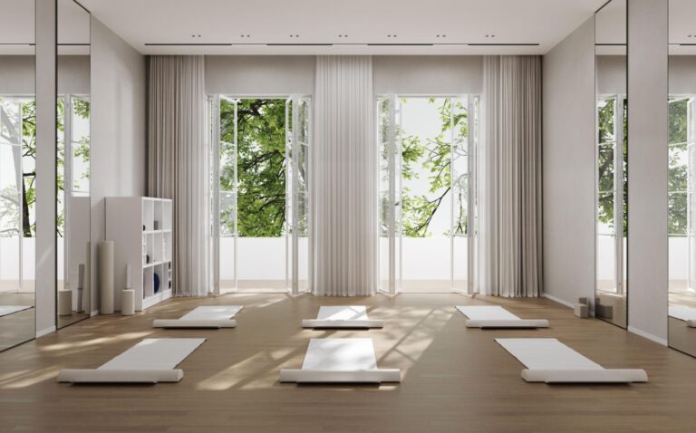 minimalist yoga retreat space with mats and natural light overlooking greenery